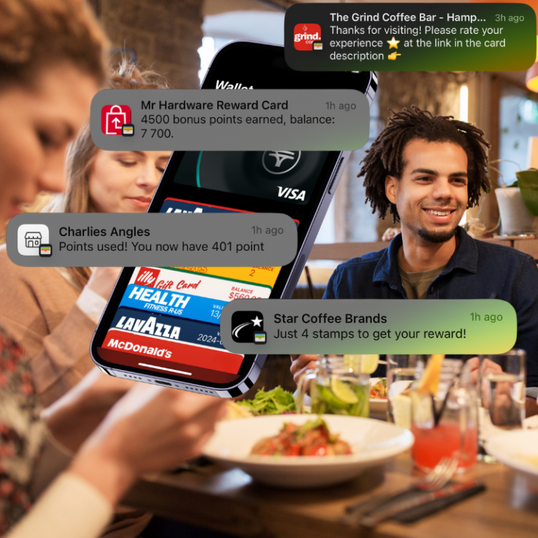 A smartphone displays several loyalty card notifications while two people sit at a table with drinks in a cafe setting.